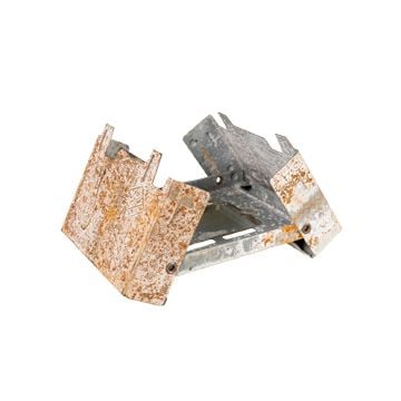 Side view of an unfolded metal fuel burner made of thin metal showing how each side folds up with light rust and corrosion on surface