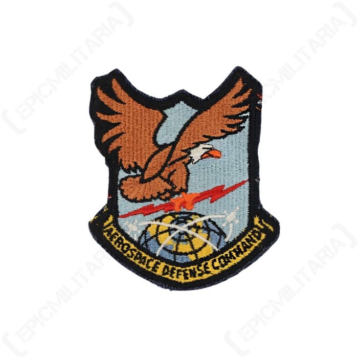 Front view of embroidered patch showing a bald eagle gripping a red lightning flash over the globe. There is a yellow scroll underneath with 'Aerospace Defense Command' written across it in black