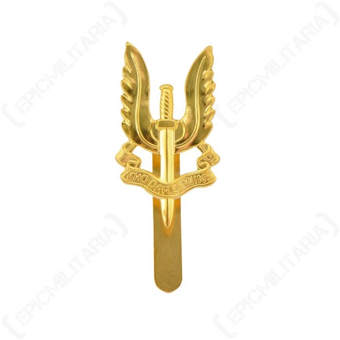 Front of a British SAS Regiment cap badge - brass showing a vertical sword pointing downward, with a pair of wings behind, and a scroll across the middle with WHO DARES WINS written on it