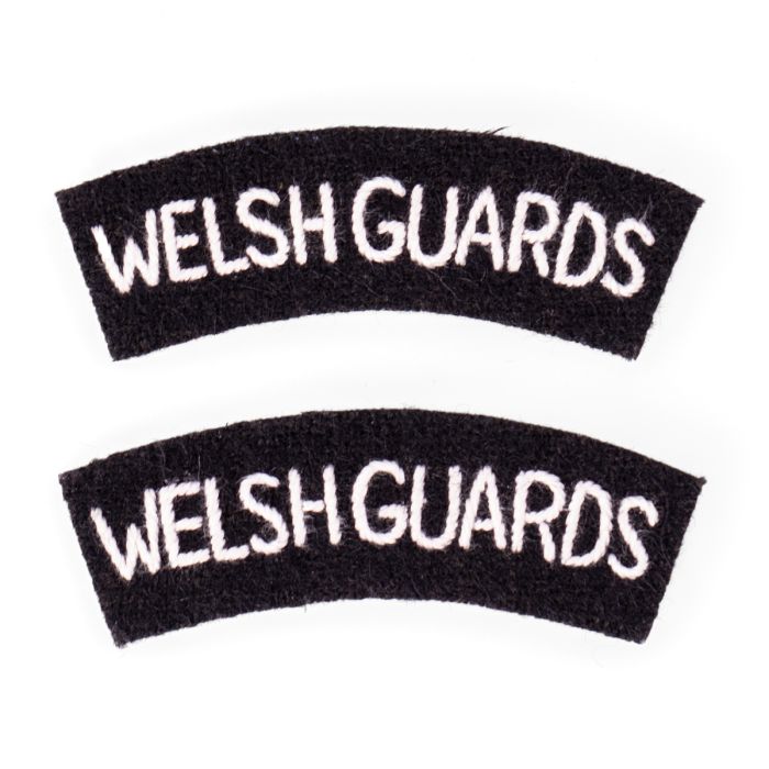 front of Welsh Guards shoulder titles showing the crescent shape made of black wool and white text that reads WELSH GUARDS 