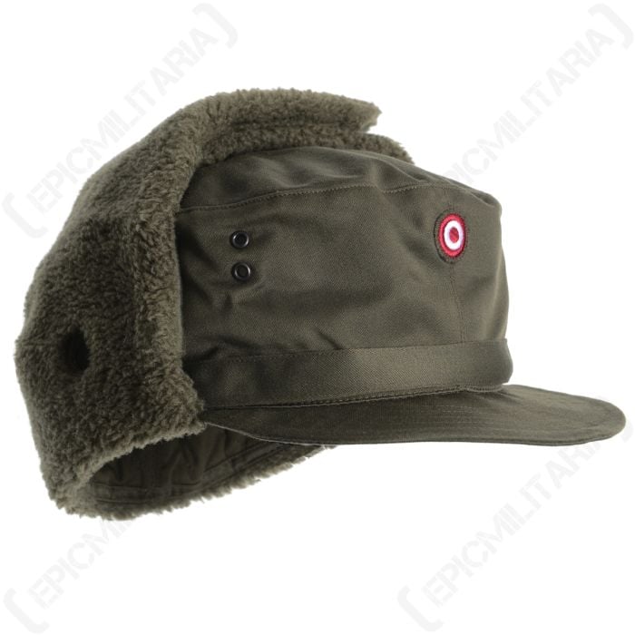 Side view of green Austrian Olive Drab Winter Cap with fleece earflaps pinned above it. Red and white cockade insignia on front.