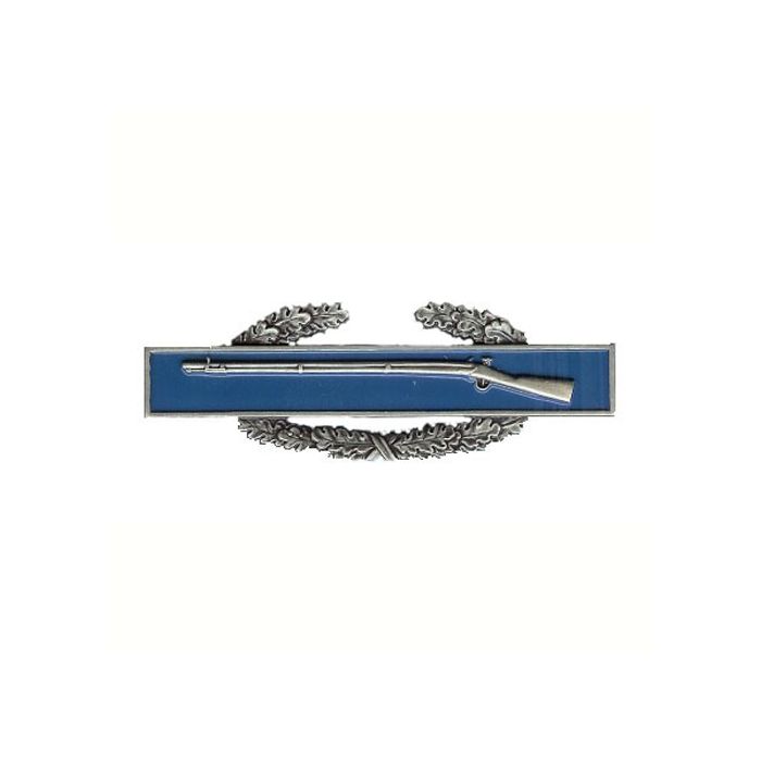 Front of Combat Infantryman 1st Award showing silver coloured right facing rifle on dark blue rectangle background, on top of a silver wreath