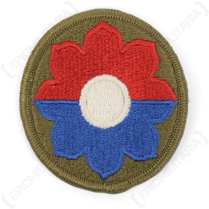 Front view of circular embroidered patch with a half blue, half red octofoil with a white circle in the middle, on a green background