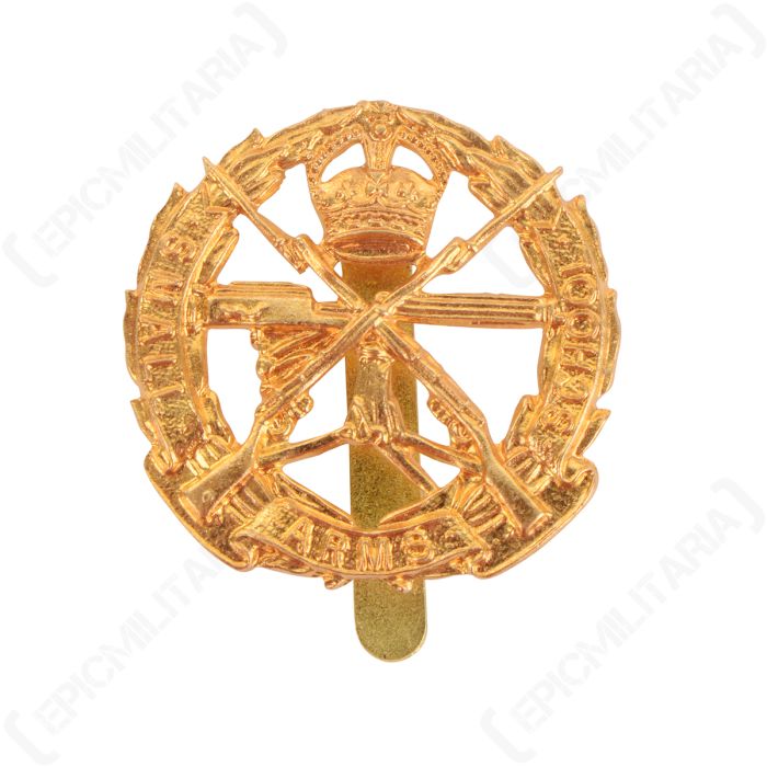 Front of gold coloured British Small Arms School Corps badge, featuring crossed rifles surrounded by a wreath