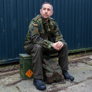 Person sat on an ammo box wearing military surplus clothing