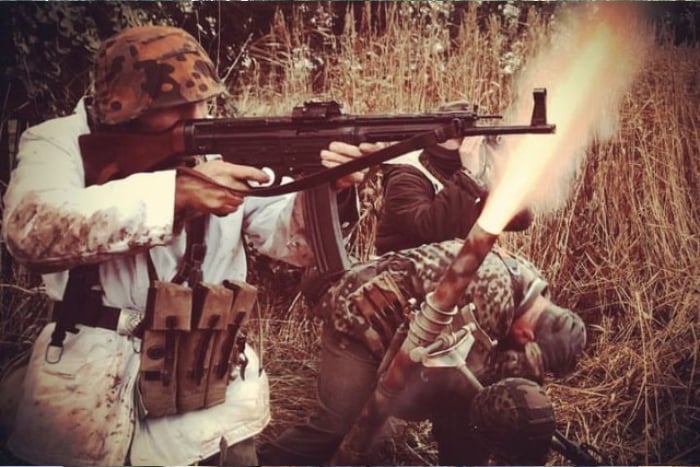 Sepia. WW2 German reenactors fire blank weapons and use a mortar