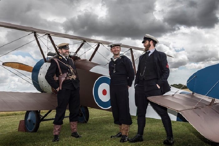 3 WW1 british Navy reenactors pose in front a British bi-plane