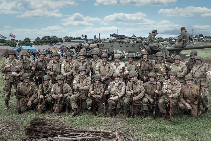 reenacctors lined up infront of a tank with ww2 us paratrooper uniforms, helmets and weapons